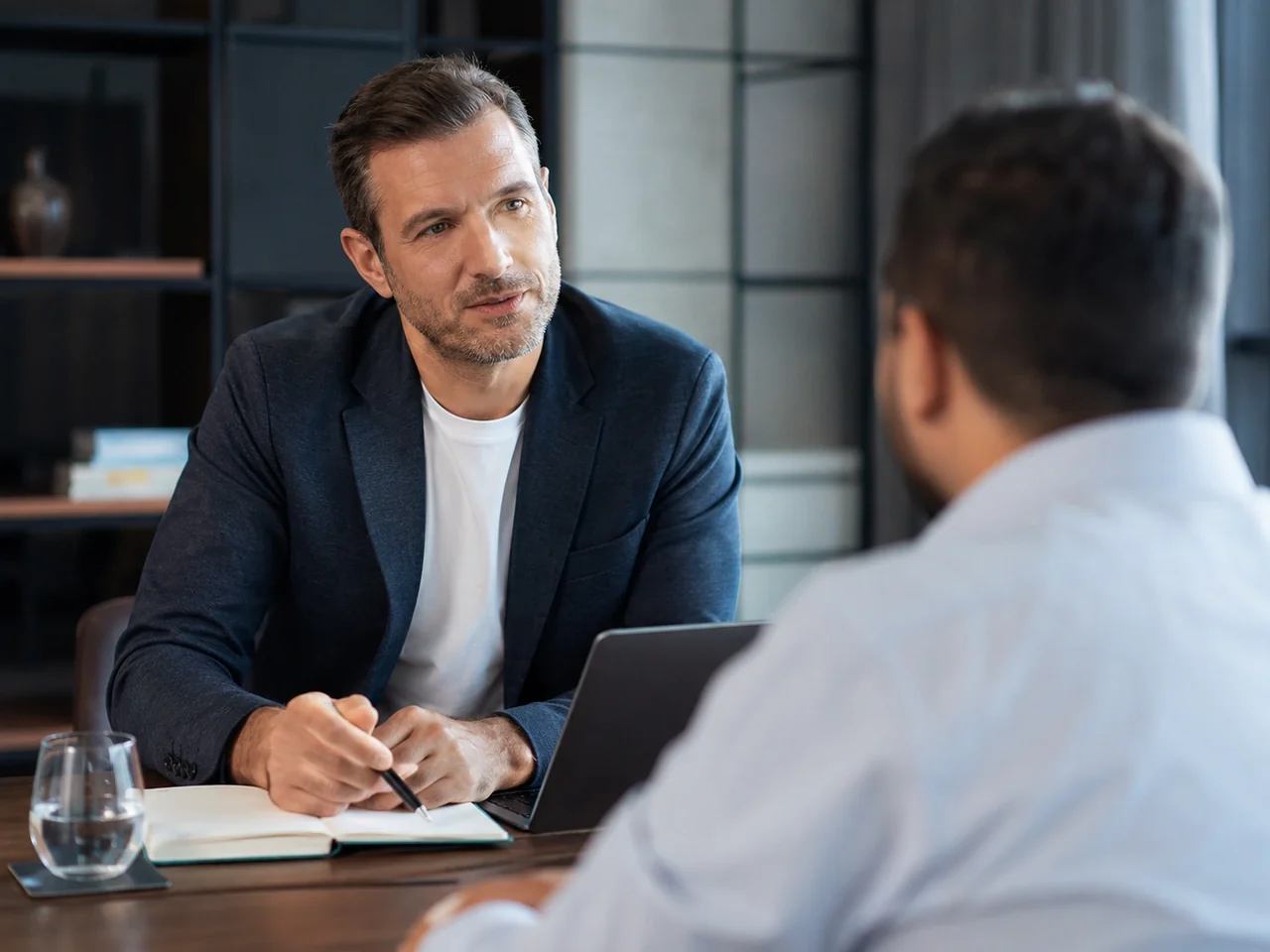 Coach executivo em sessão de coaching de carreira com cliente em sala de reunião — sistema de agendamento para coaches