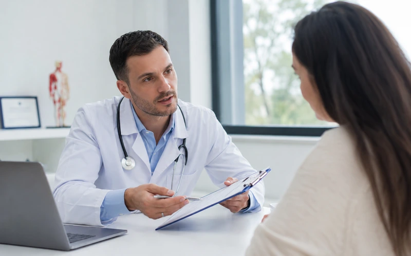 Médico revisando a ficha do paciente em consulta no consultório — sistema de agendamento para médicos